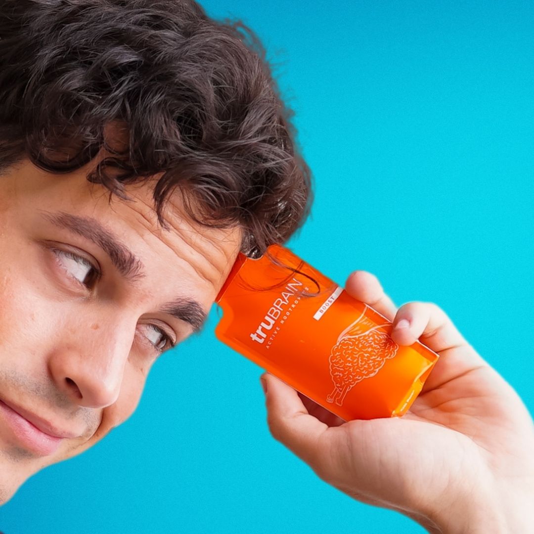 Handsome, successful and intelligent young male professional holding up a packet of the best nootropics 2022 up to his forehead while looking at it with a curious and optimistic look